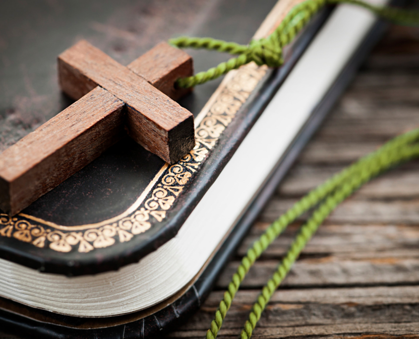 wooden cross on bible with green necklace