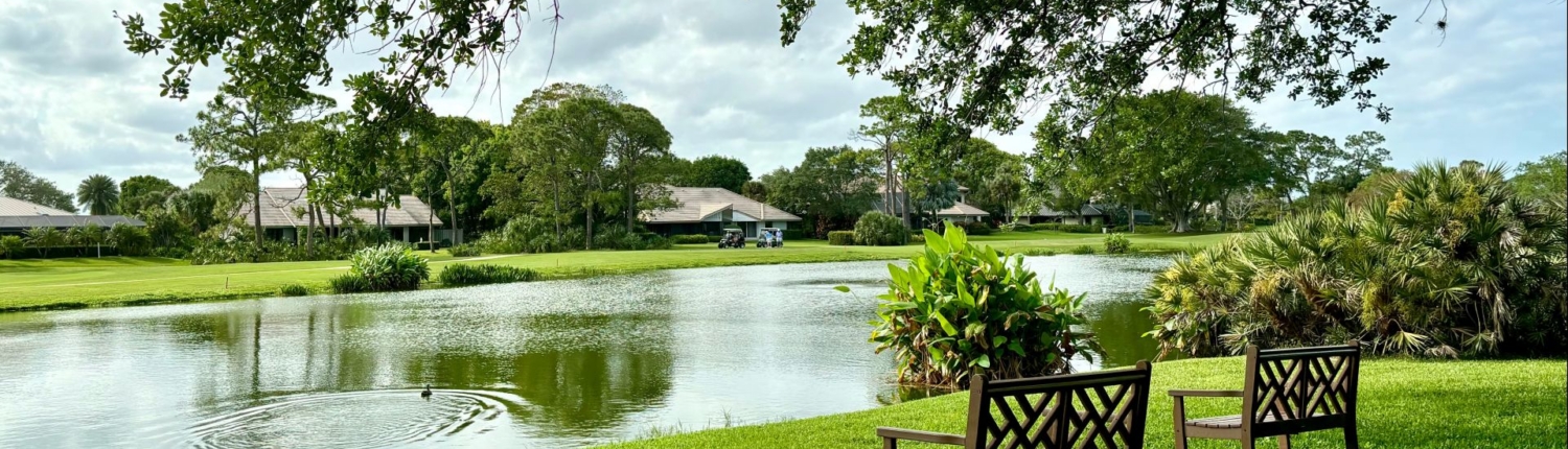 two wooden benches overlooking lake and golf course