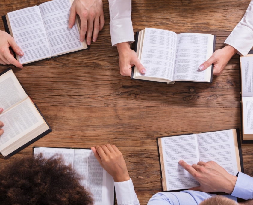 six open bibles on table with people reading them