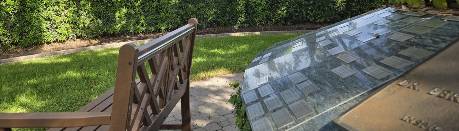 Closeup of plaques on circular flower garden with bench facing out