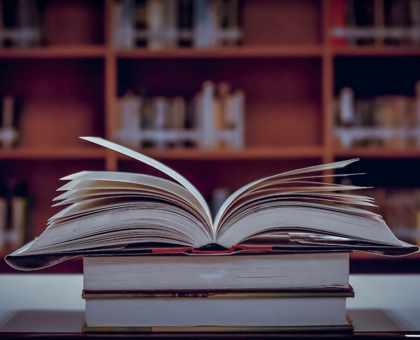 open book on table in front of shelves with books