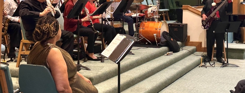 Orchestra with singer and bass guitar playing in front of chapel