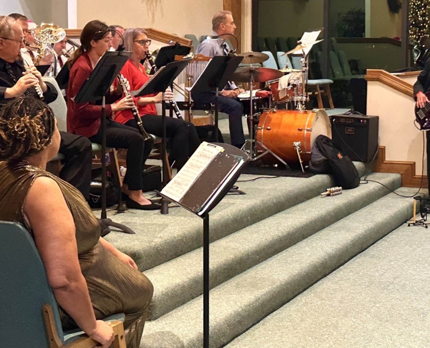 Orchestra with singer and bass guitar playing in front of chapel
