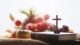 Wooden cross on brown bible with pumpkins, fruit and vegetables on a table