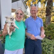 Woman holding small dog with her husband watching