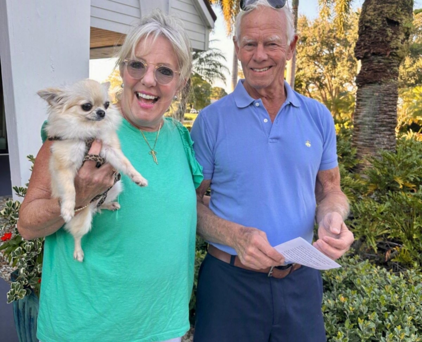 Woman holding small dog with her husband watching