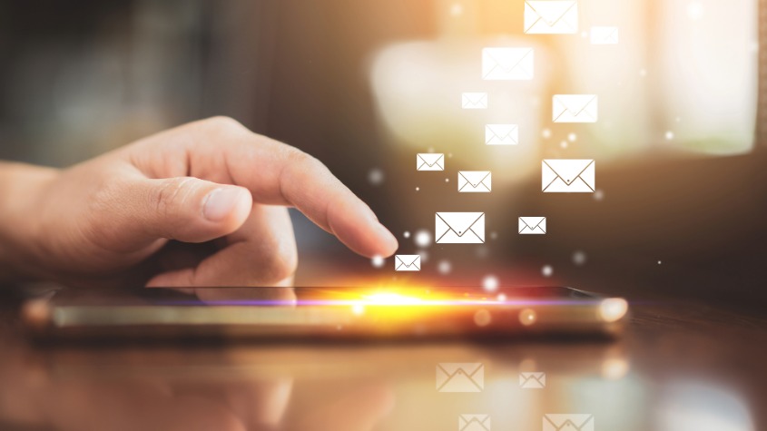 hand hovering over smartphone with email icons flying above phone