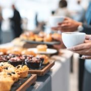 Coffee Time Muffins on table with coffee mug held in woman's hand.