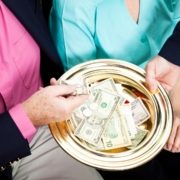 Ushers Usher handing collection plate to women in church