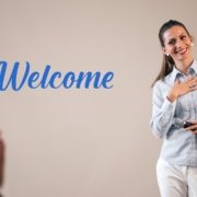 woman with microphone standing in front of white video screen